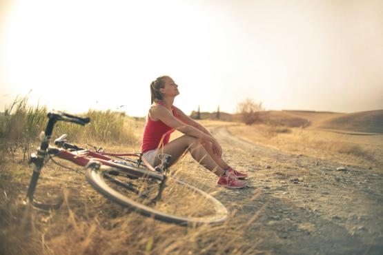 Foto door Andrea Piacquadio: https://www.pexels.com/nl-nl/foto/sportieve-vrouw-met-fiets-die-op-plattelandsweg-in-zonlicht-rust-3771836/